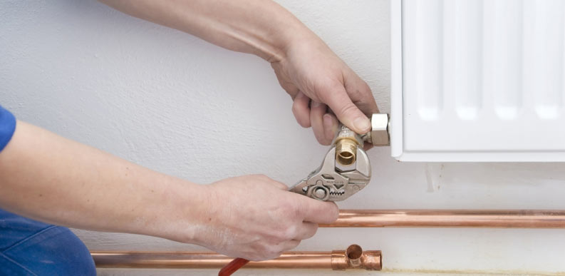 Plumber working on radiator valves